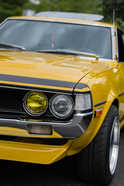 the front of an old car painted yellow