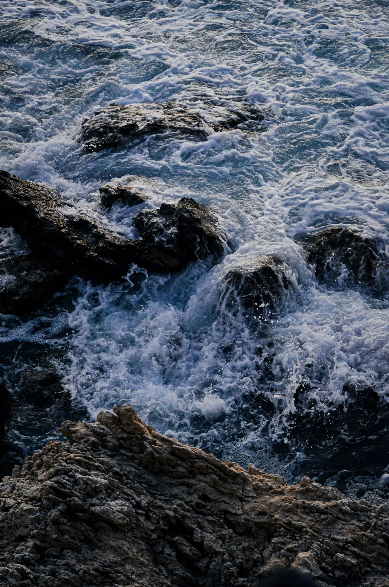 rocks near a body of water with foamy water