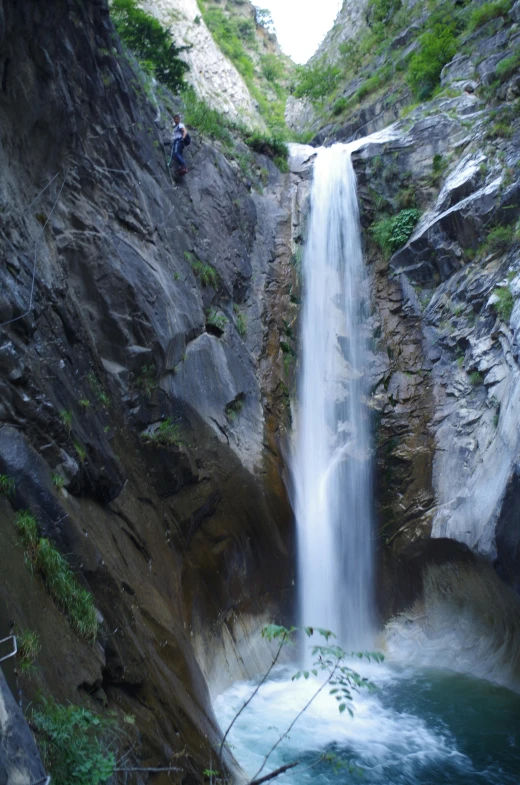 a man standing on a waterfall near a body of water