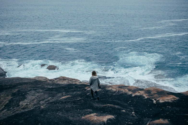 a woman looking out at the ocean from a rock cliff