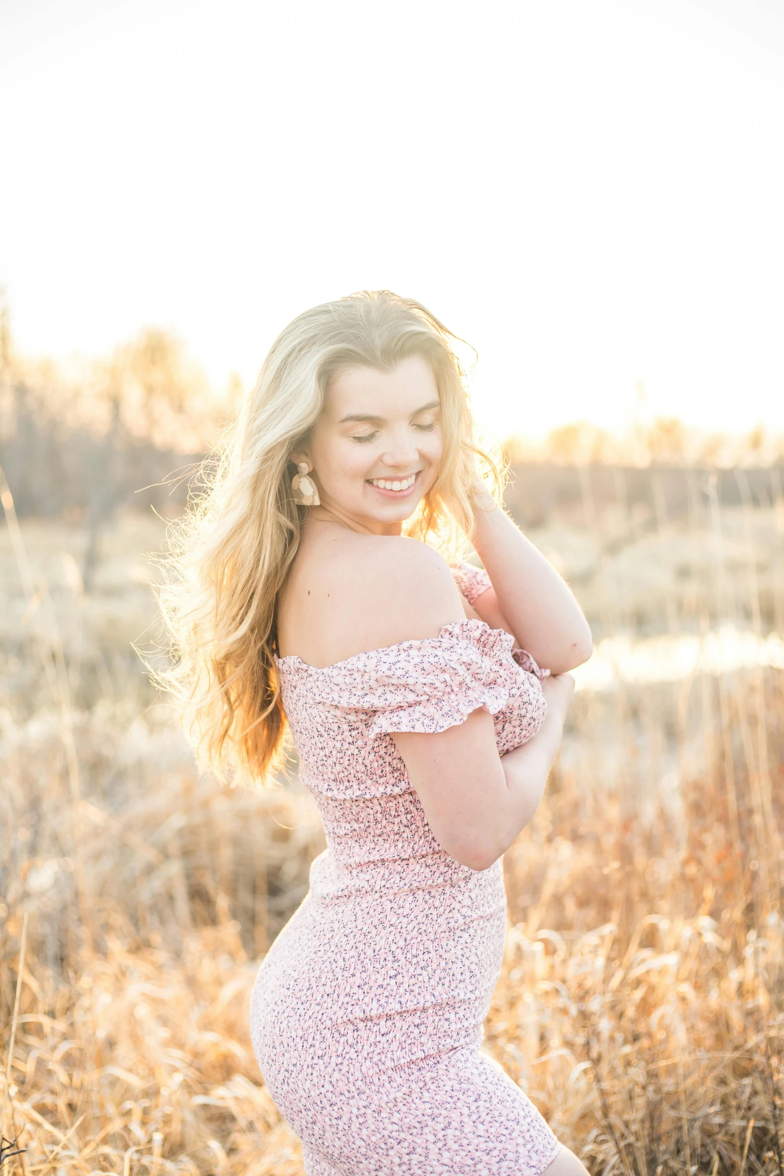 a smiling  with long blond hair posing in tall grass