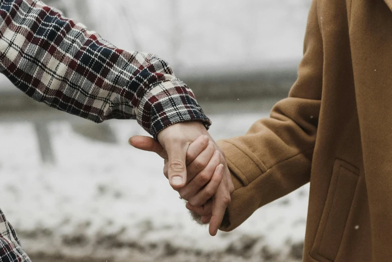 two people standing in the snow with their hands held together