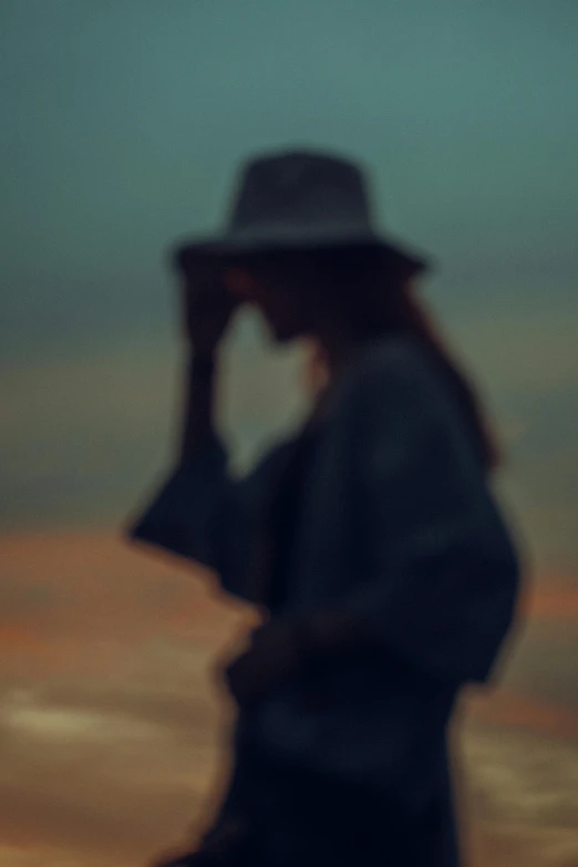 a man standing on the beach in a hat