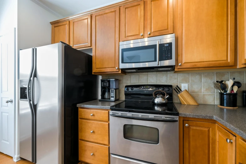 a kitchen with wooden cabinets, stainless steel refrigerator and stove