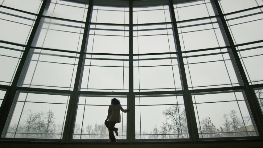 a woman standing inside of a big building looking out the window