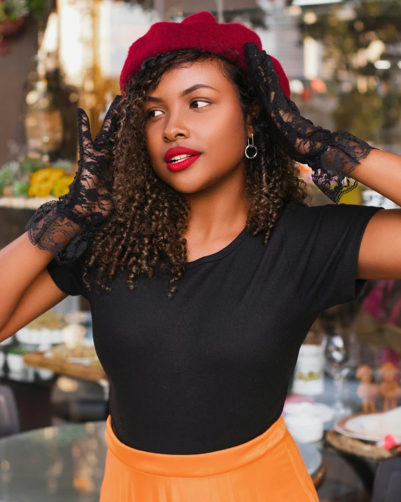 the woman wears a black top with orange a skirt and a red hat