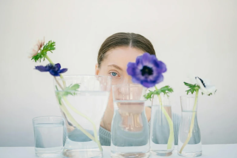 girl in glasses looking up while holding blue flowers