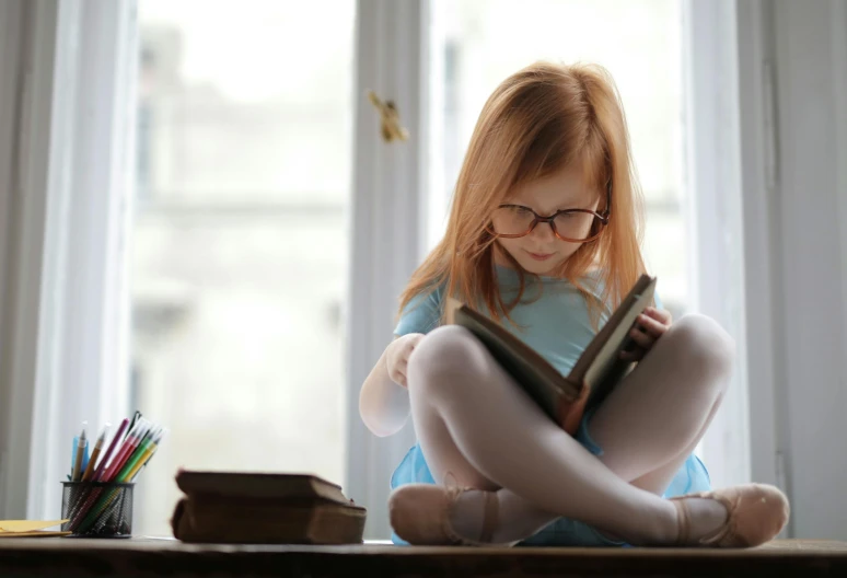 the girl is reading her book while she sits on the table