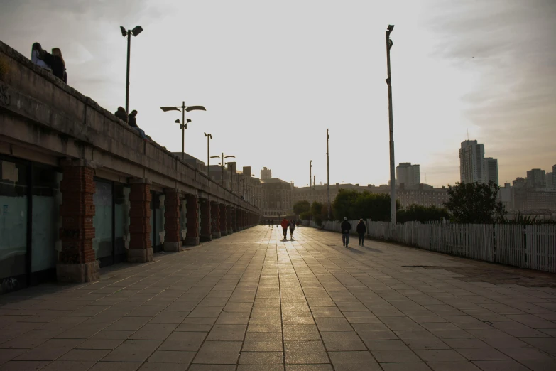 two people walking down the sidewalk in front of store fronts