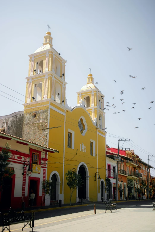 a large building with multiple levels in front of it and birds flying in the air