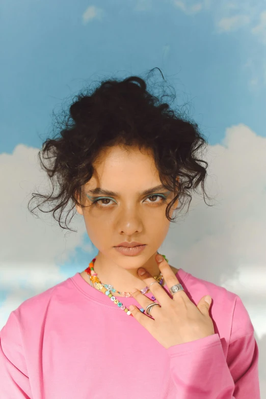 a woman in pink shirt with necklace on cloudy sky