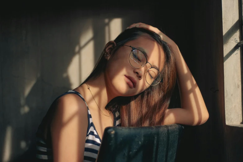 a woman in striped shirt and glasses posing by window