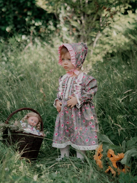 a little girl with her doll is holding a basket