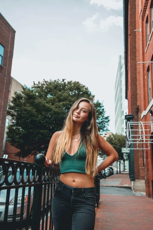 a woman is standing near a fence on the street