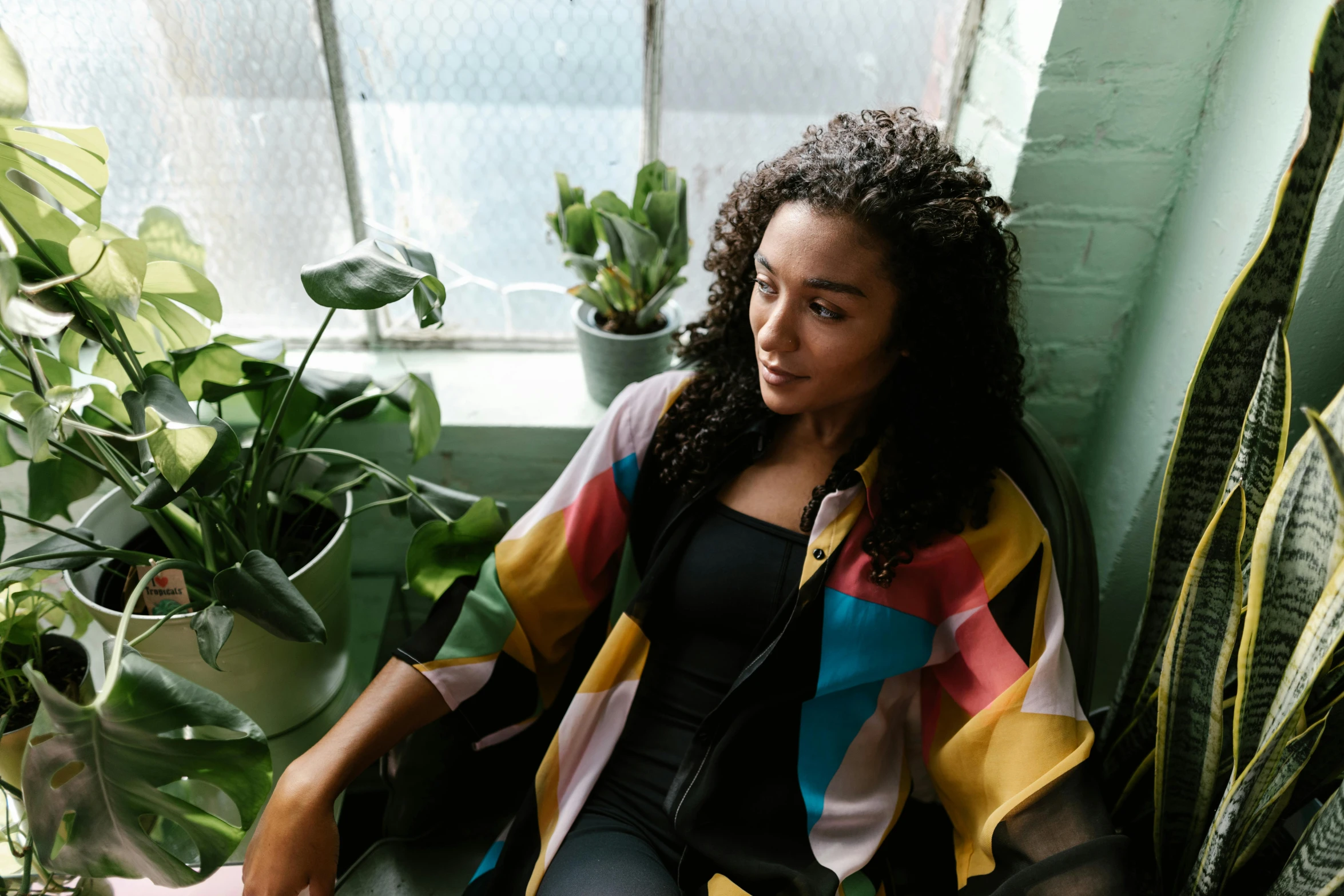 a woman is sitting in front of plants