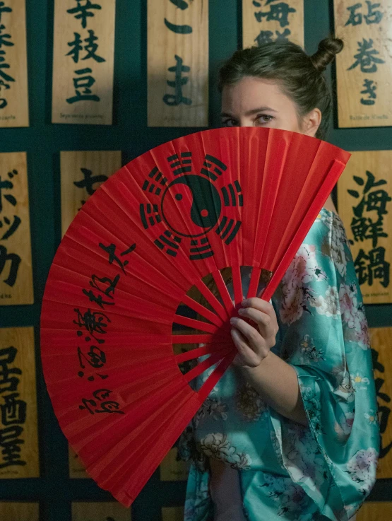 a girl is holding an oriental fan over her shoulder