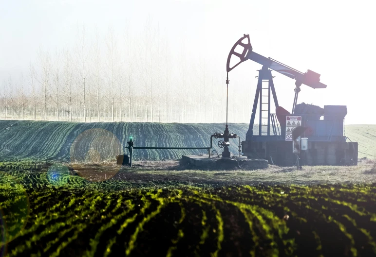 an oil pump in the field next to some trees