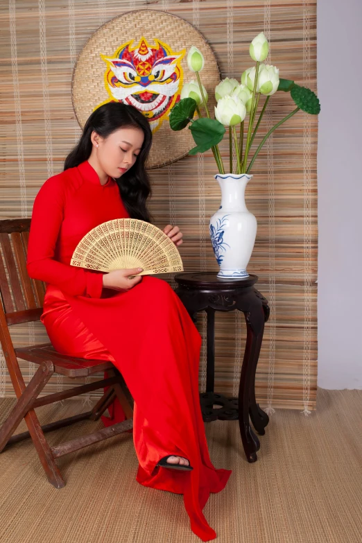 a beautiful lady sitting next to a flower vase