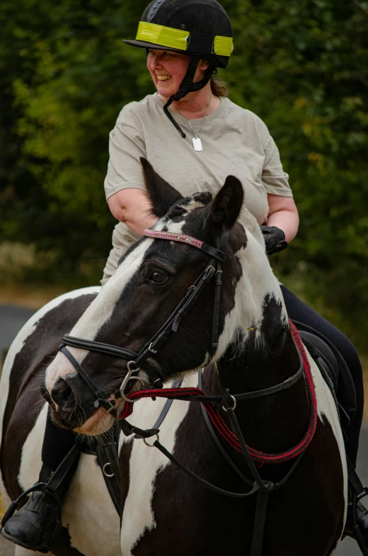 a woman riding a brown and white horse with a black face and yellow ear tags