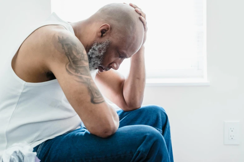 a man is sitting on a toilet with his hand to his ear