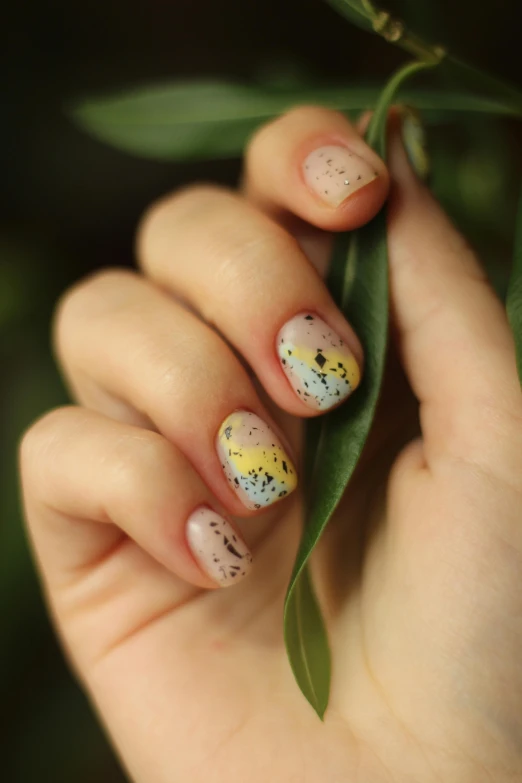 a woman with a nail polish on her nails is holding onto a leaf