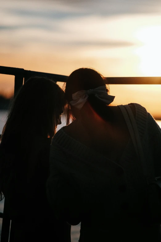 two people are standing close together in silhouette