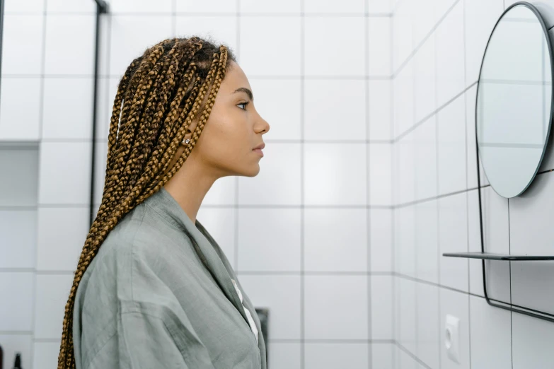 a woman with twists on her hair stands in the bathroom near the mirror