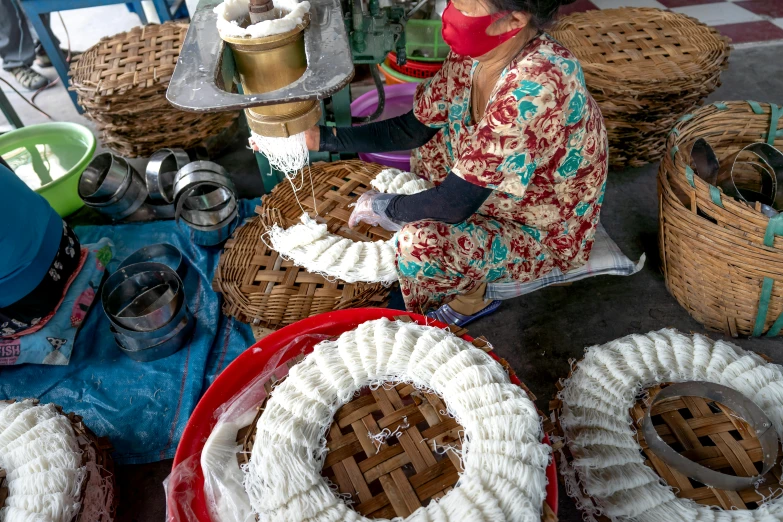 a woman sitting down between baskets of food and a pie