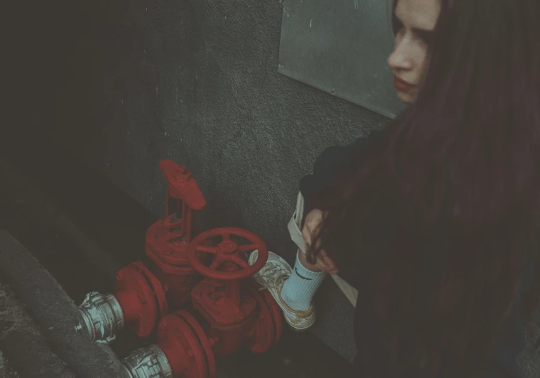 a young woman is standing by a red hydrant