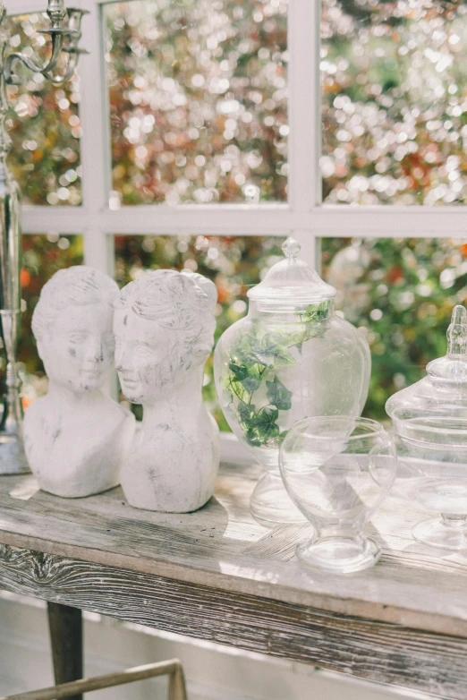 there is a glass and plastic vases on a table