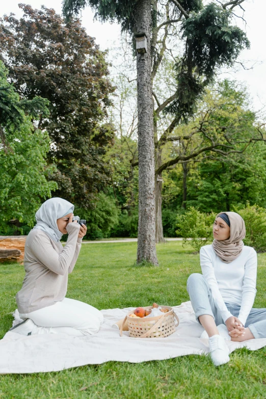 two woman sitting down with one taking a po