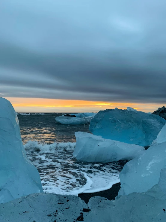 a couple of ice blocks in the water at sunset