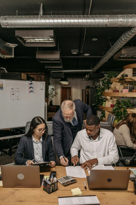 three employees working together in an office with laptops and computers