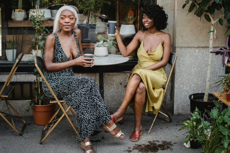 two woman sit on chairs eating outside