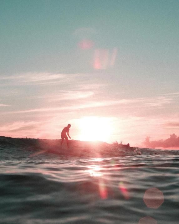 surfer catching a wave in the ocean at sunset