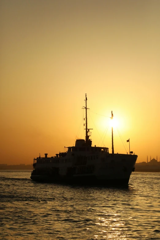 a small boat sails into the setting sun