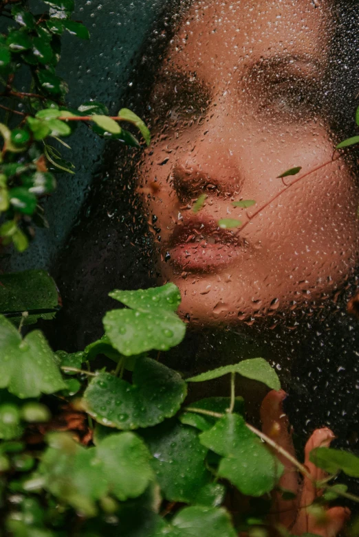 a woman is seen through a rain - streaked glass