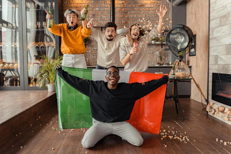 three men in sweaters, two on the ground, and one with his arms up