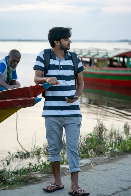 man in striped shirt standing next to a boat