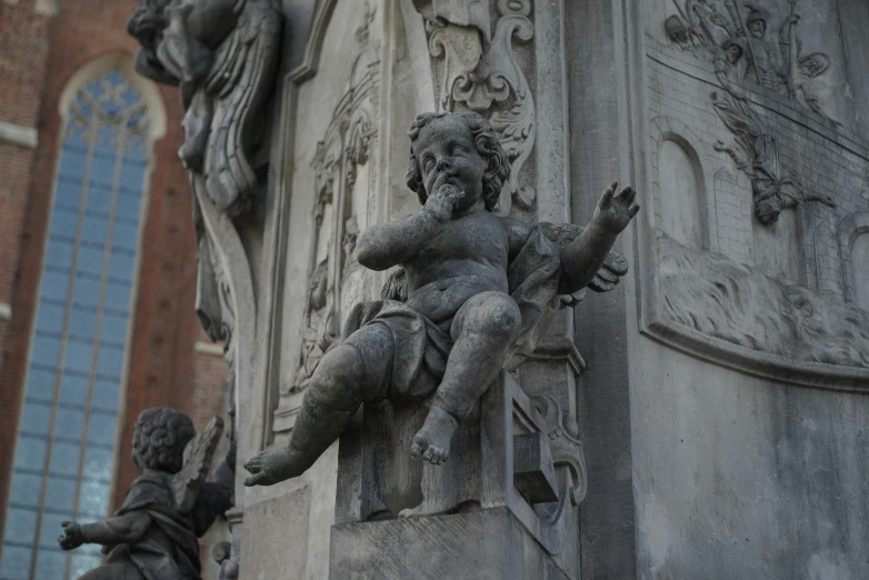 sculpture on top of pillar of old building with window in background