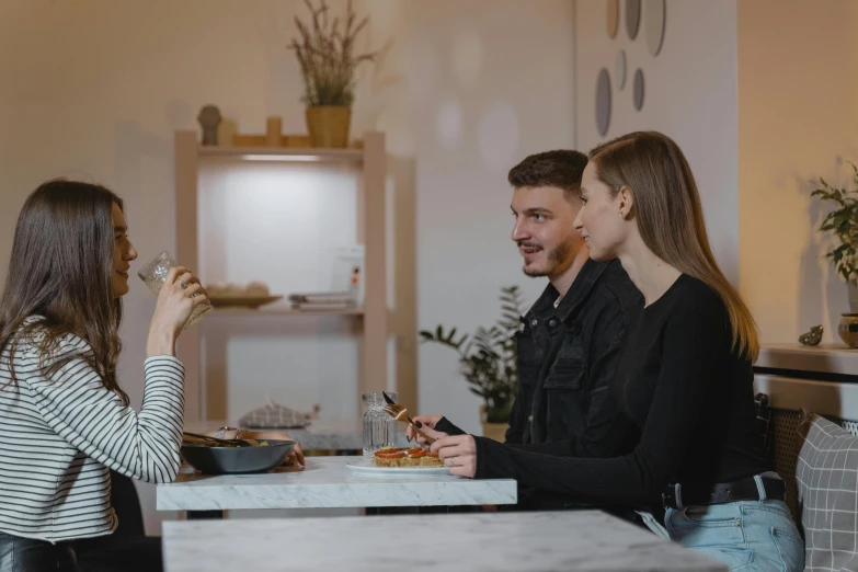 three people are sitting at a table with food