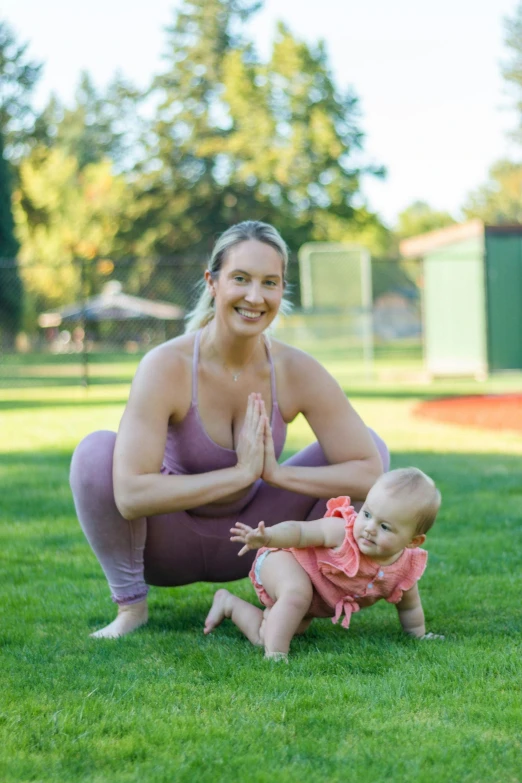 a woman squats while holding onto a small baby