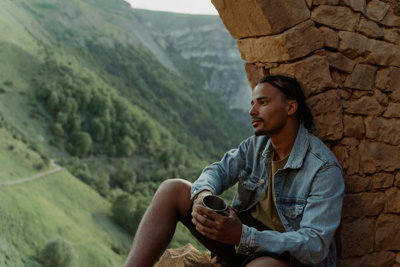 a man sitting on the side of a rocky cliff