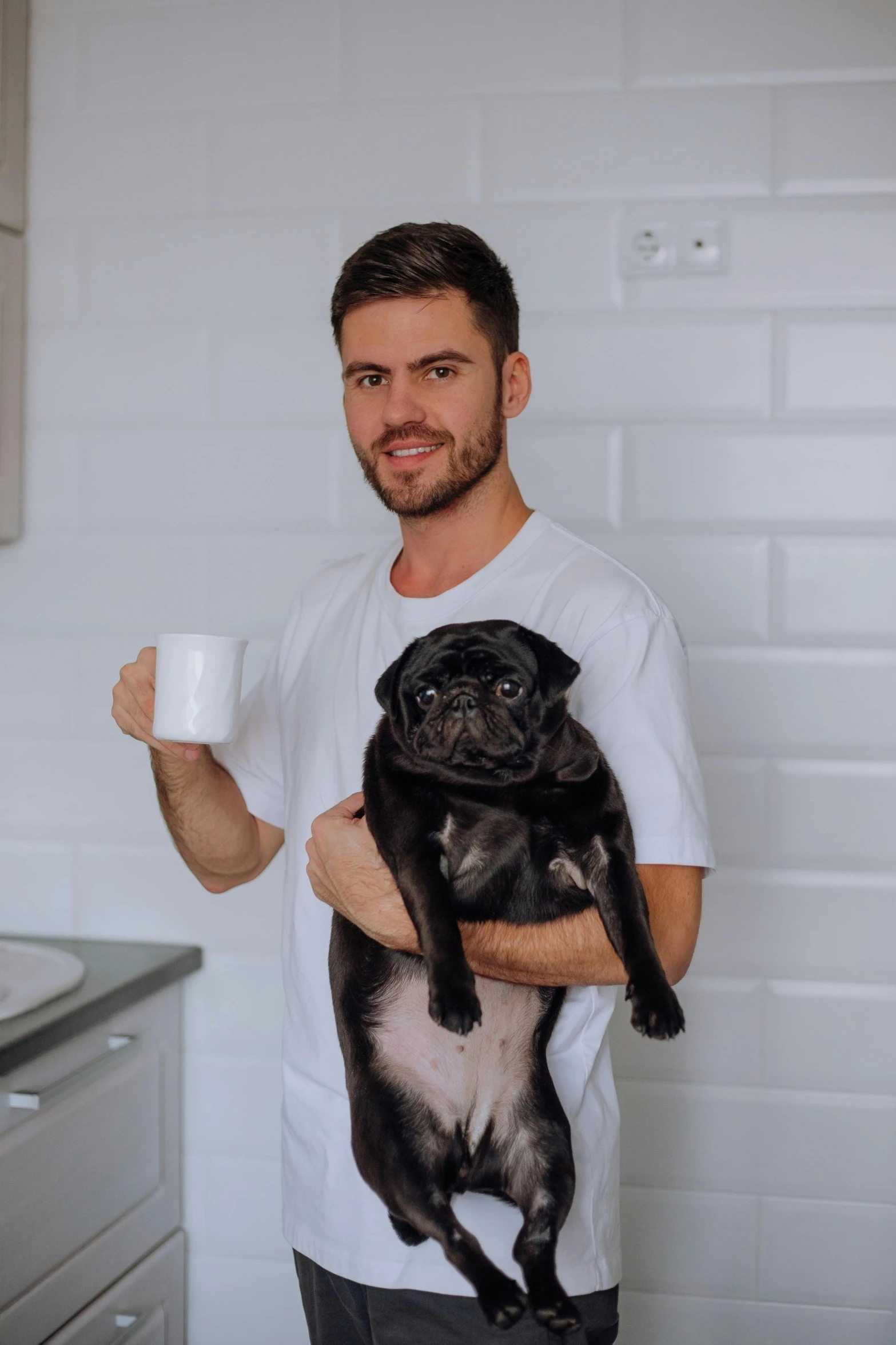 a man holding a small dog holding a mug