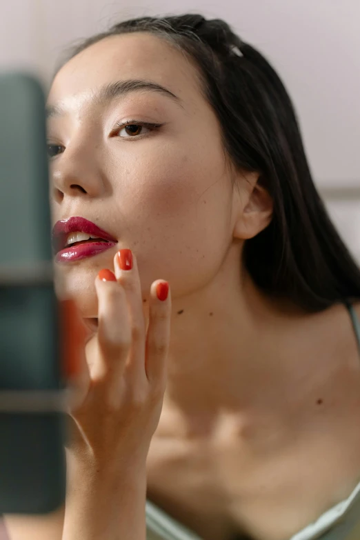 woman looking at mirror with fingers to her face