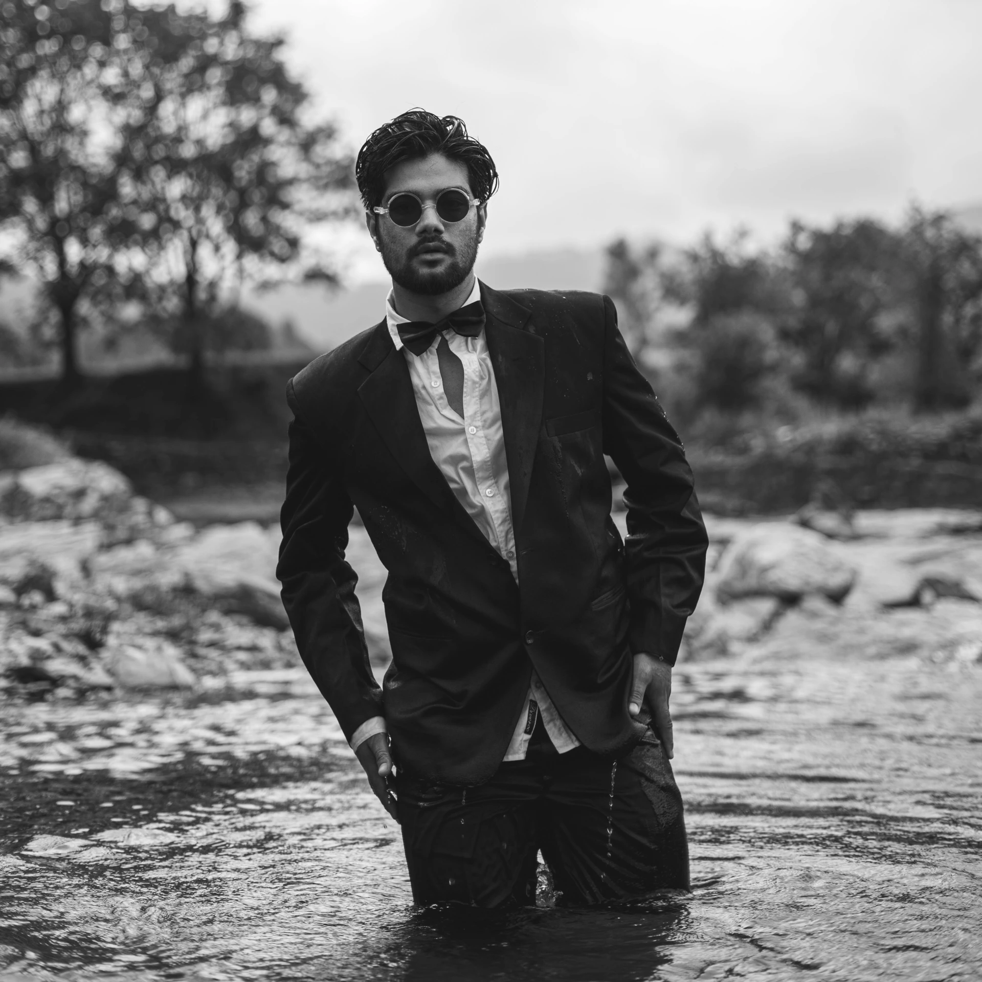 black and white pograph of man standing in shallow river