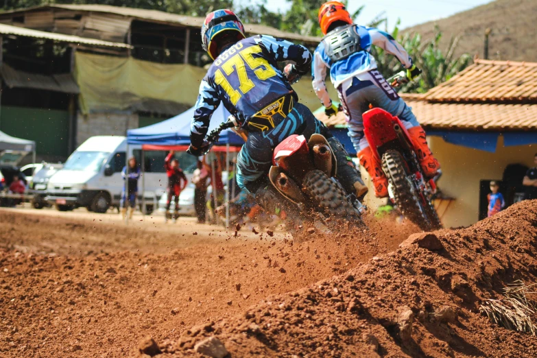 two people riding dirt bikes on top of a dirt track