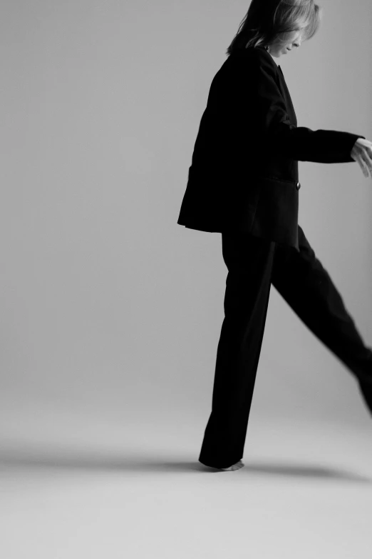 a woman wearing a suit is dancing in black and white