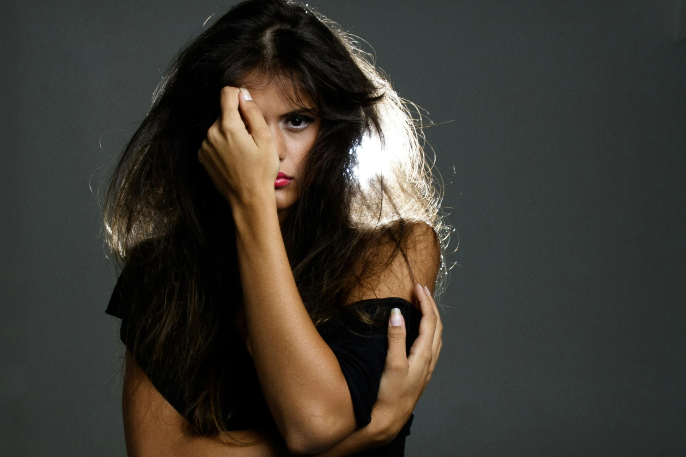 a woman in black is holding her hair