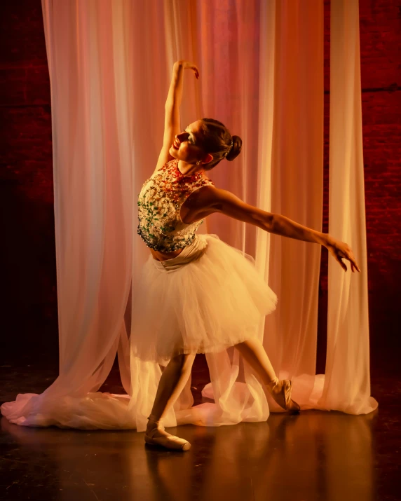 a young ballerina performs in front of curtains
